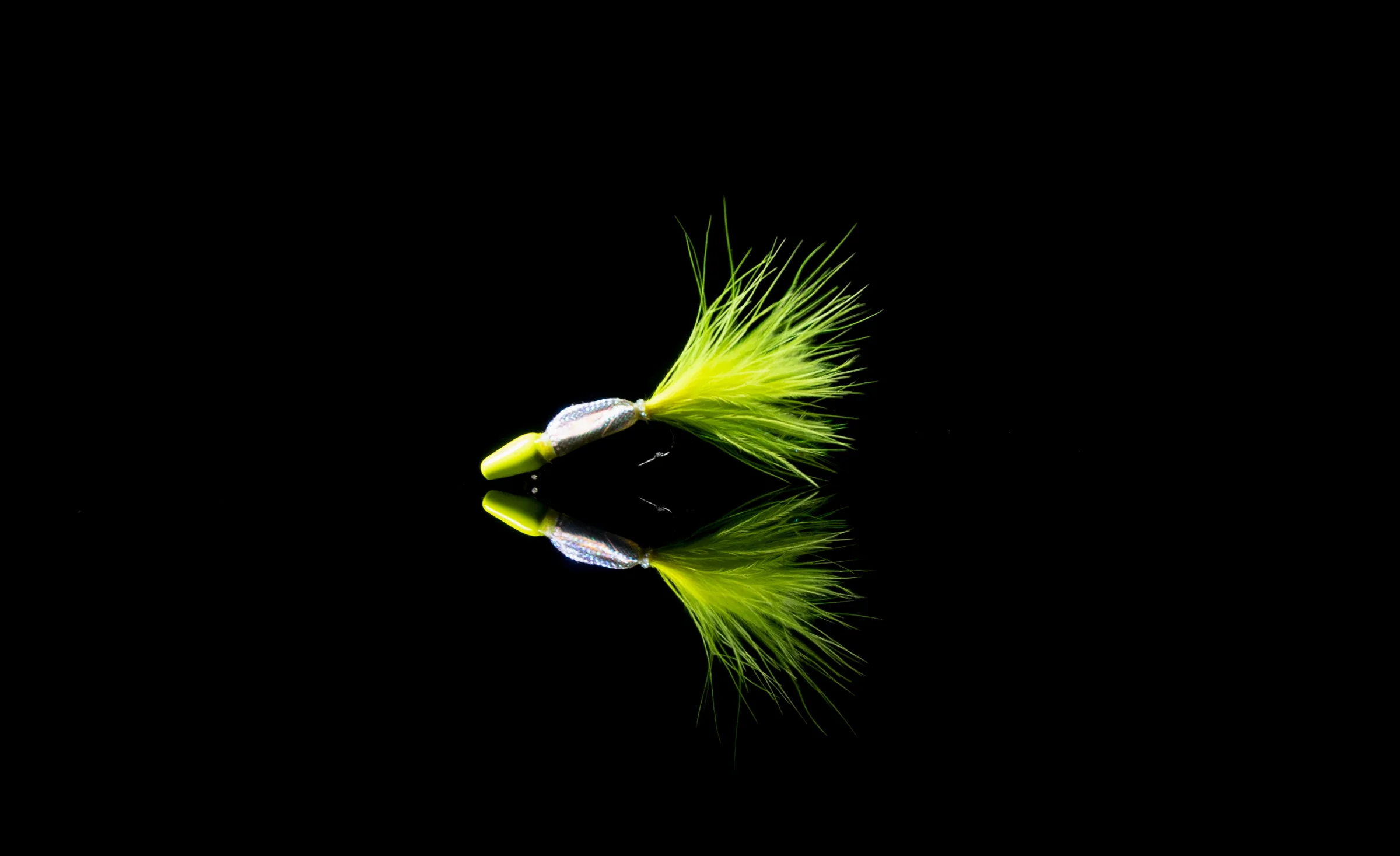 A hand-tied FishHawk marabou jig mirrored on still, dark water